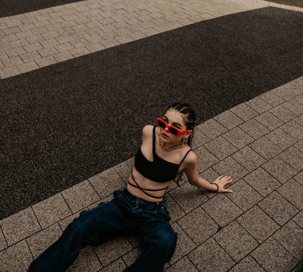 our-story-01 Stylish woman in a crop top and sunglasses posing on a tiled walkway.