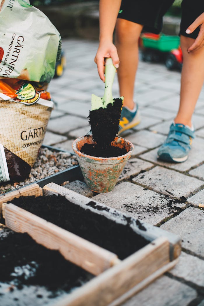 our-story-02 A child actively participates in gardening by shoveling soil into a pot on a patio.